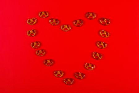 Mini pretzels in the shape of heart lie on vibrant red background. Pretzel Sunday conceptの写真素材