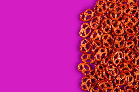 Border of mini pretzels on fuksia background. Vibrabt color backdrop with Salted bitesの写真素材