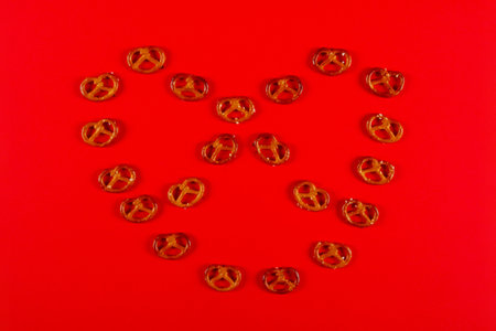 Mini pretzels in the shape of knot lie on vibrant red background. Pretzel Sunday conceptの写真素材
