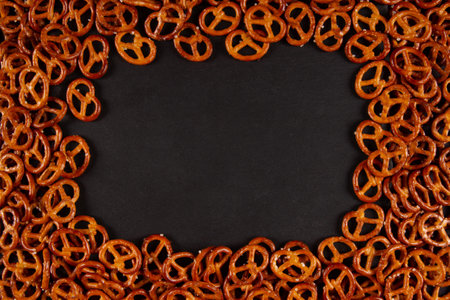 Rectangular frame of mini pretzels on black background. Dark backdrop with Crunchy twistsの写真素材