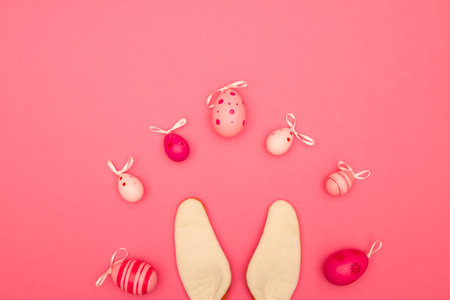 Celebrate Easter with a pink background that includes copy space, Easter eggs, and bunny earsの写真素材