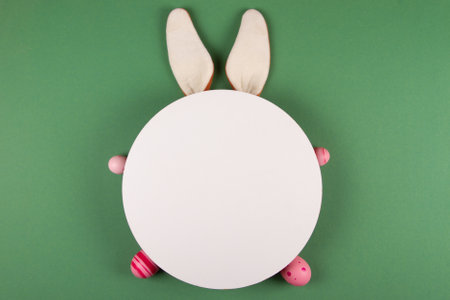Easter eggs, white circles, and bunny ears decorate a green backgroundの写真素材