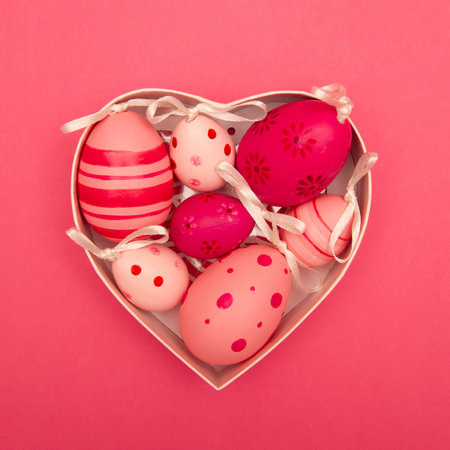 Easter eggs in the heart shaped box on pink backgroundの写真素材