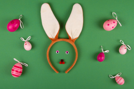 Funny easter green background with pink eggs and bunny faceの写真素材