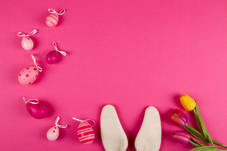 Pink Easter background with copy space, Easter eggs, tulips and bunny ears