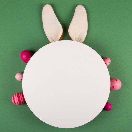 Bunny ears, white circle and Easter eggs on green backgroundの写真素材