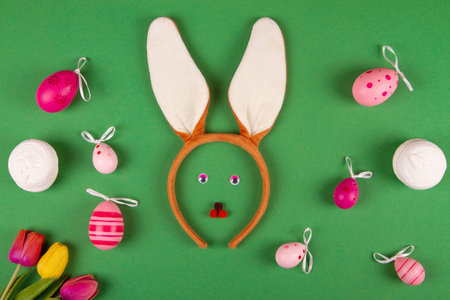 Comical Easter backdrop in shades of green, showcasing pink eggs and a bunny faceの写真素材
