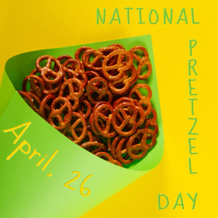 Close-up of Mini pretzels in light green paper cone lie on yellow background. National Pretzel day concept observed on April 26の写真素材