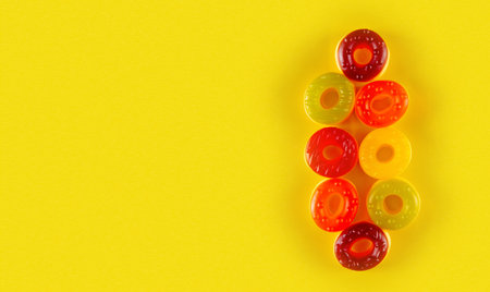 Eight round jelly candies lie on yellow background. Eye-catching circular confections on bold surfaceの写真素材