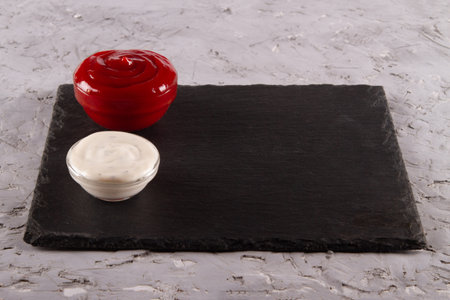 Red and white dipping sauces on black slate serving board with blank space. Heavenly Sauce Harmony.の写真素材