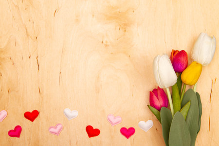 Tulip flowers and small herts on wooden background with copy space. Love charm meets floral charm.の写真素材