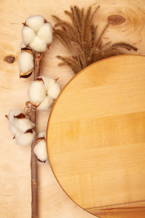 Fluffy decorative spikelets and cotton flowers on wooden background with copy space. Vintage-inspired greeting card with wooden and floral accents.の写真素材