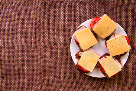 Ham & cheese Homemade sandwiches on white plate on burlap with copy spaceの写真素材