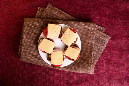 Sendwiches with tomatoes, ham and cheese on burlap background. Quick snack conceptの写真素材