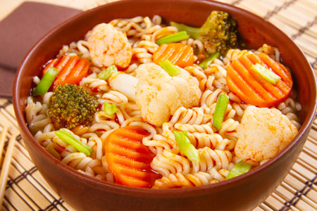 Bowl of asian noodles with vegetables on light bamboo background close-upの写真素材