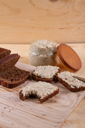 Dark bread with spread on wooden background, adding touch of warmth and charm.の写真素材