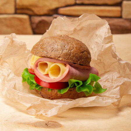 Delicious sandwich with ham, tomatoes, cheese and green lettuce on wooden background close-upの写真素材