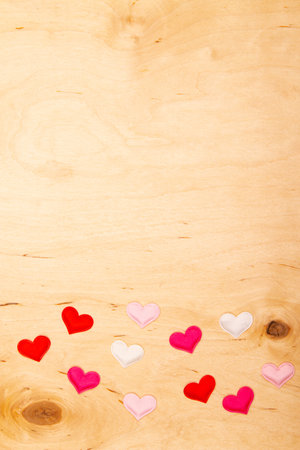 A lot of small hearts on wooden background with copy space. Delicate hearts create a heartfelt Valentine's day greeting card.の写真素材