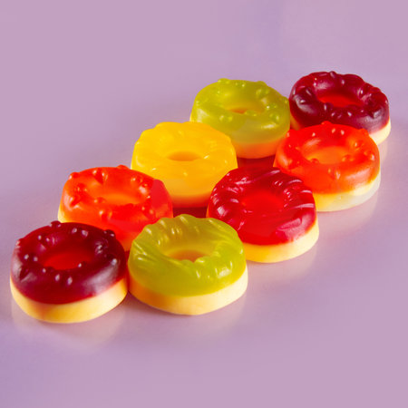 Eight round jelly candies lie on purple background. Sugary, circular delights on colorful backdropの写真素材