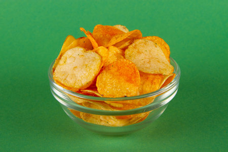 Potato chips in glass bowl isolated on green background. SIDE viewの写真素材