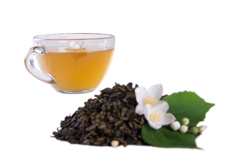 Dried tea leaves, fresh jasmine blossoms with green leaf and glass tea cup showcased in isolation against white backdropの写真素材