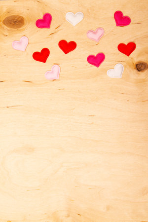 A lot of small hearts on wooden background with copy space. Scattered hearts enhance wooden greeting card.の写真素材