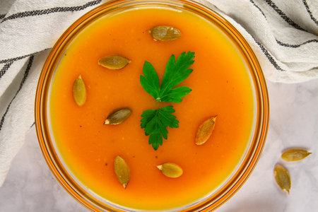 Close-up top view of delightful pumpkin soup garnished with pumpkin seeds and greens.の写真素材