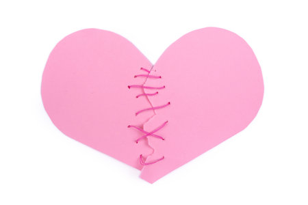 Torn in half paper heart sewn with pink threads isolated on white backgroundの写真素材