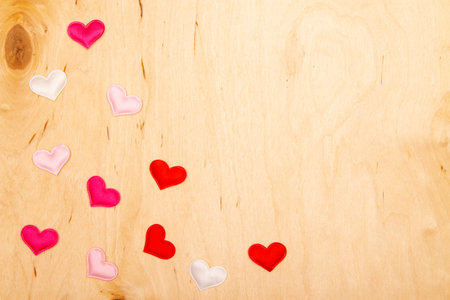 A lot of small hearts on wooden background with copy space. Greeting card with Wooden rustic charm and heartfelt symbols.の写真素材