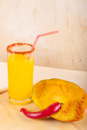 Mangonada mexican mango smoothie with chamoy sauce and chili powder seasoning on wooden backgroundの写真素材