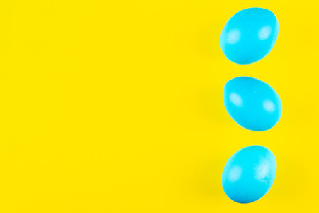 Three blue easter eggs on vivid yellow background with copy space make vibrant catch eye easter bannerの写真素材