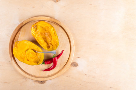 Top view of two halves of mango, two red hot chili peppers and spoon on wooden background with copy spaceの写真素材