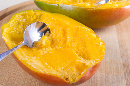Side view of halve of mango and spoon on wooden backgroundの写真素材