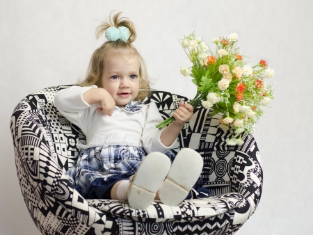 A little girl sat on a chair with a bouquet of flowersの写真素材