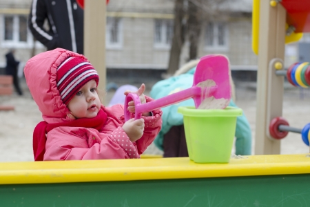  The little girl pours sand in the bucket in the sandboxの写真素材