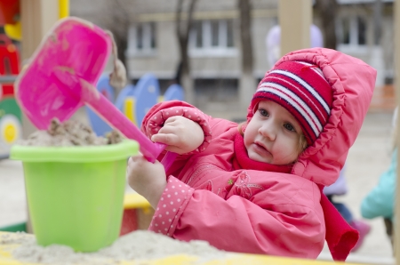  The little girl pours sand in the bucket in the sandboxの写真素材