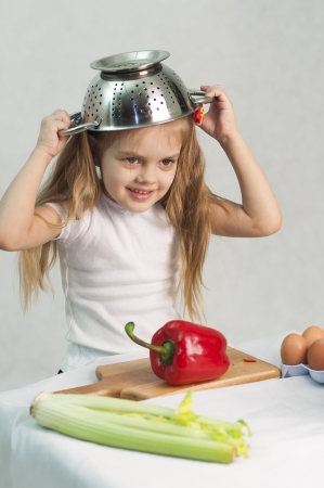 Girl playing in the cook put on a colander on his headの写真素材
