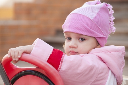 Two-year-old girl thoughtfully looks sitting on a bikeの写真素材
