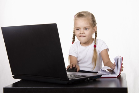 The girl sitting at the table, working at a laptop, and records in a notebook
