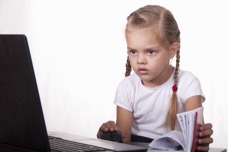 The girl working at a laptop, leafing through a diaryの写真素材
