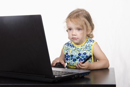 The girl sitting at the table, working at a laptop, and holding a penの写真素材