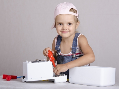 Girl repairs screwdriver toy microwaveの写真素材