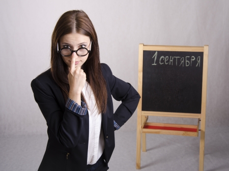 Portrait of the teacher Ð¿Ð¾Ð¿ÑÐ°Ð²Ð»ÑÑÑÐµÐ³Ð¾ spectacles on his nose and Board in the backgroundの写真素材