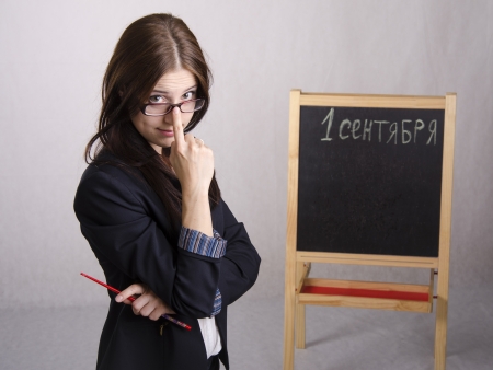 Portrait of the teacher Ð¿Ð¾Ð¿ÑÐ°Ð²Ð»ÑÑÑÐµÐ³Ð¾ spectacles on his nose and Board in the backgroundの写真素材