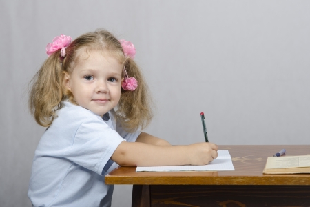 Little girl sitting at the table and wrote in a notebookの写真素材