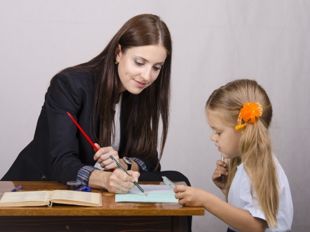 The teacher teaches lessons with a student sitting at the tableの写真素材