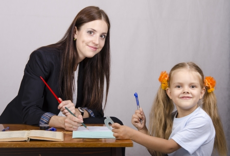 The teacher teaches lessons with a student sitting at the tableの写真素材