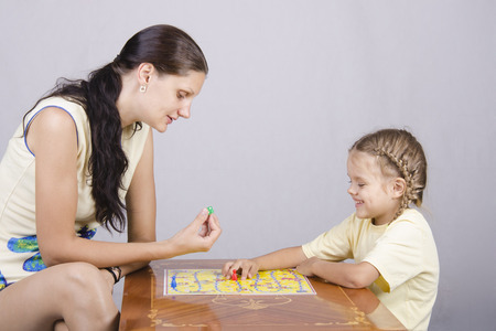 Mother and daughter sitting at a table and play a Board gameの写真素材