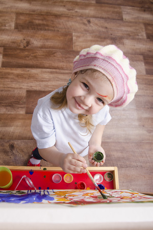 Three-year-old girl playing in the artist. Girl draws on the easel paintsの写真素材
