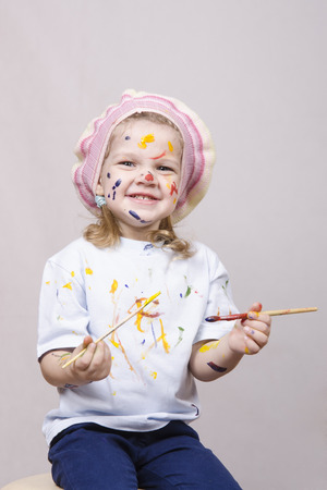 Portrait of a three-year old girl playing in the artist. Girl mud paintsの写真素材